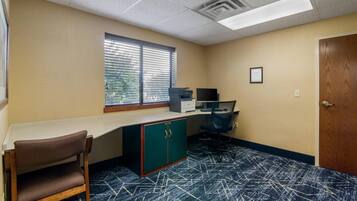 A room with a desk, chair, and a window with blinds.