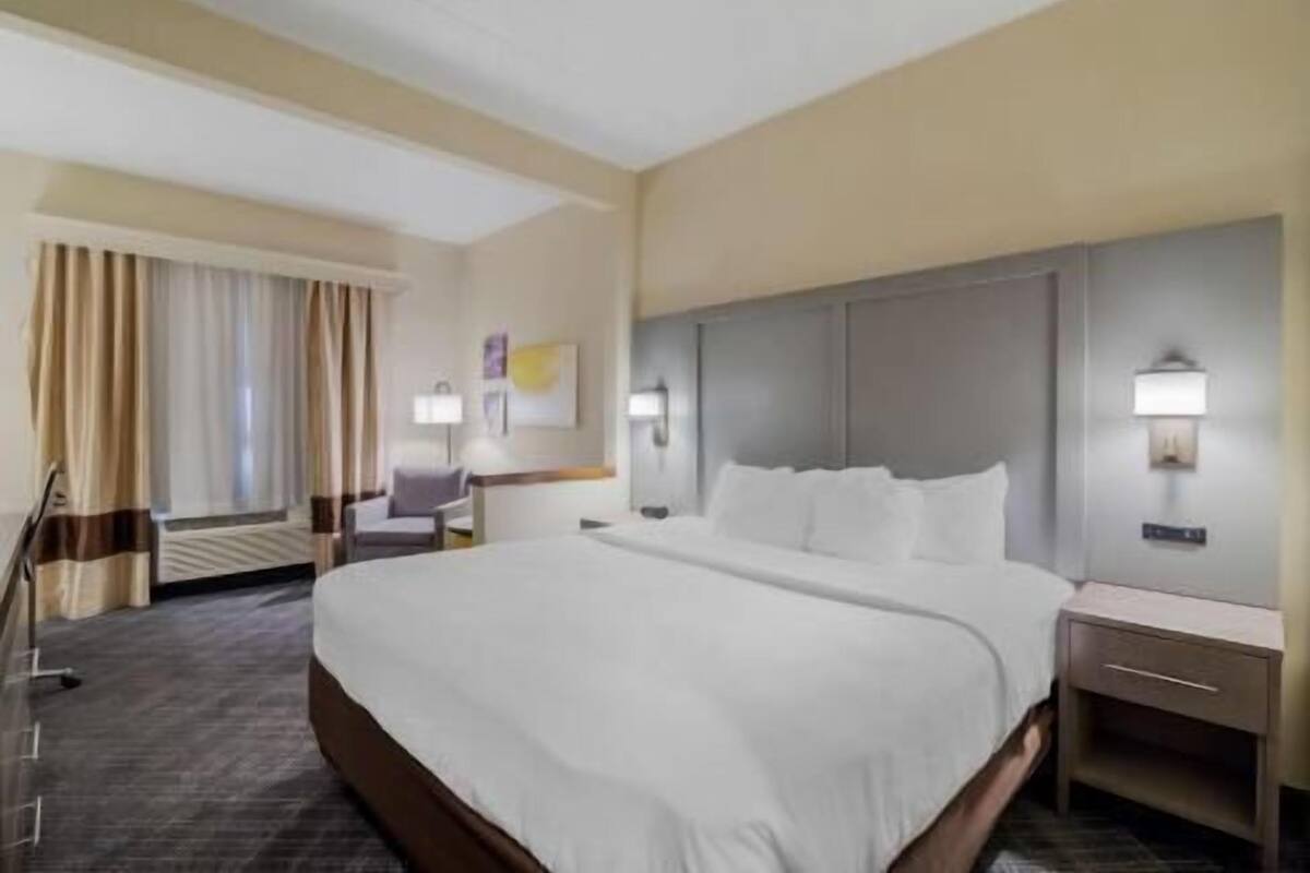 A hotel room with a large bed, bedside tables, a chair, and a desk.