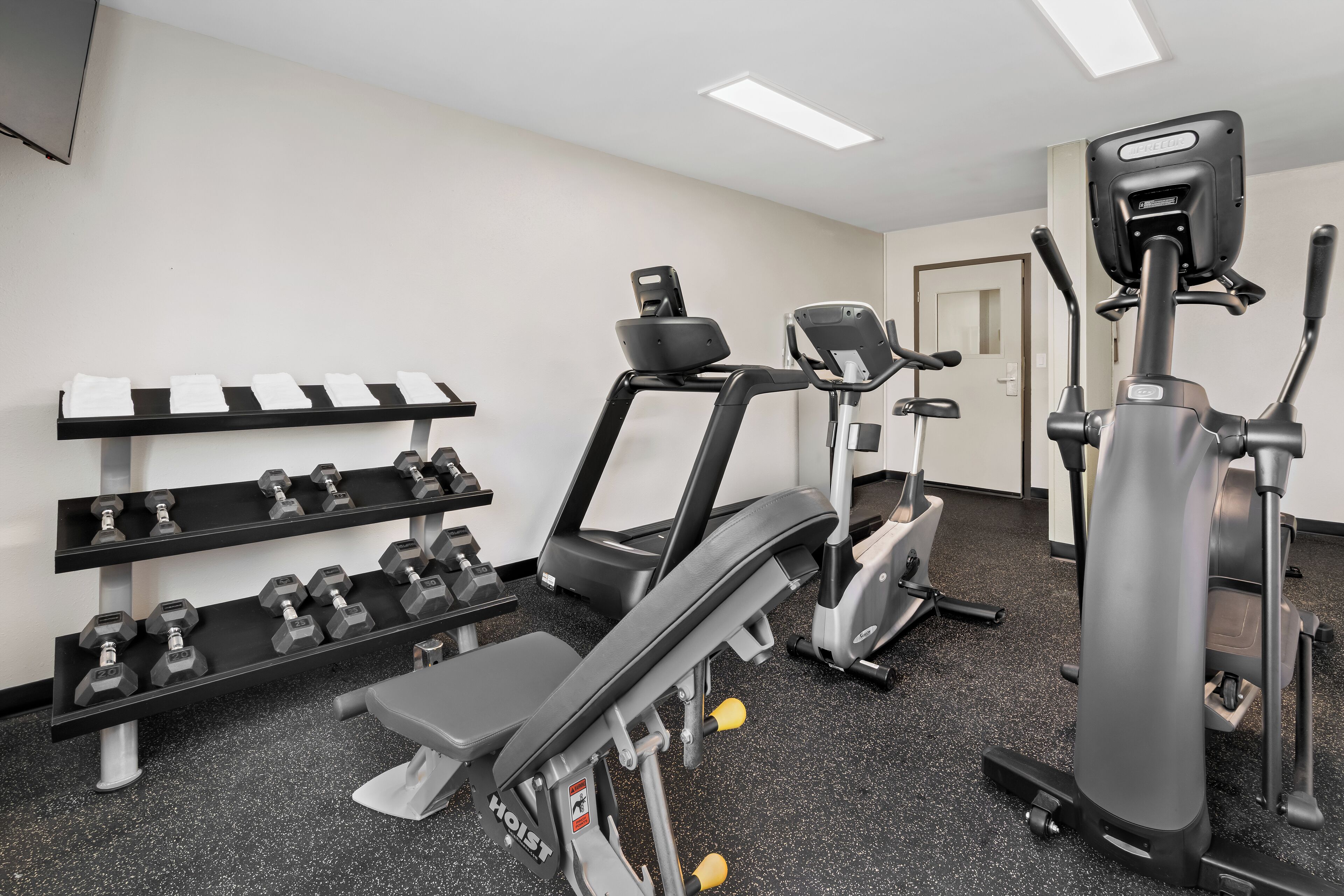 Une salle de sport équipée de tapis de course, de vélos elliptiques et d’haltères.