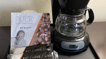 Una cafetera con un filtro de café y un paquete de café sobre una bandeja.