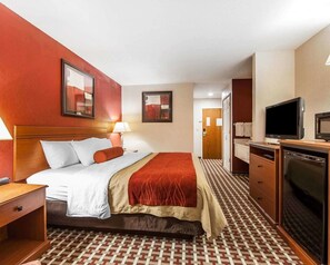 A hotel room with a bed, a desk, a television, and a bathroom visible in the background.