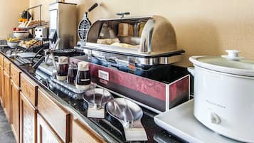 Montaje de un bufé de desayuno con diversos alimentos, una estación de café y una olla de cocción lenta.