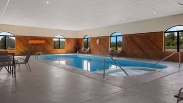 Un área interior de piscina moderna con una pared de madera, piscina y zona de estar con sillas.
