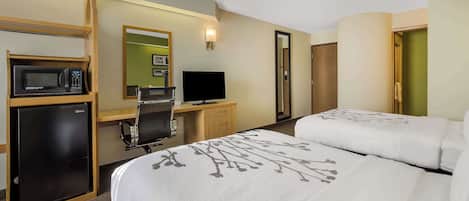 Een hotelkamer met een bed, een bureau met een computer, een magnetron en een televisie.
