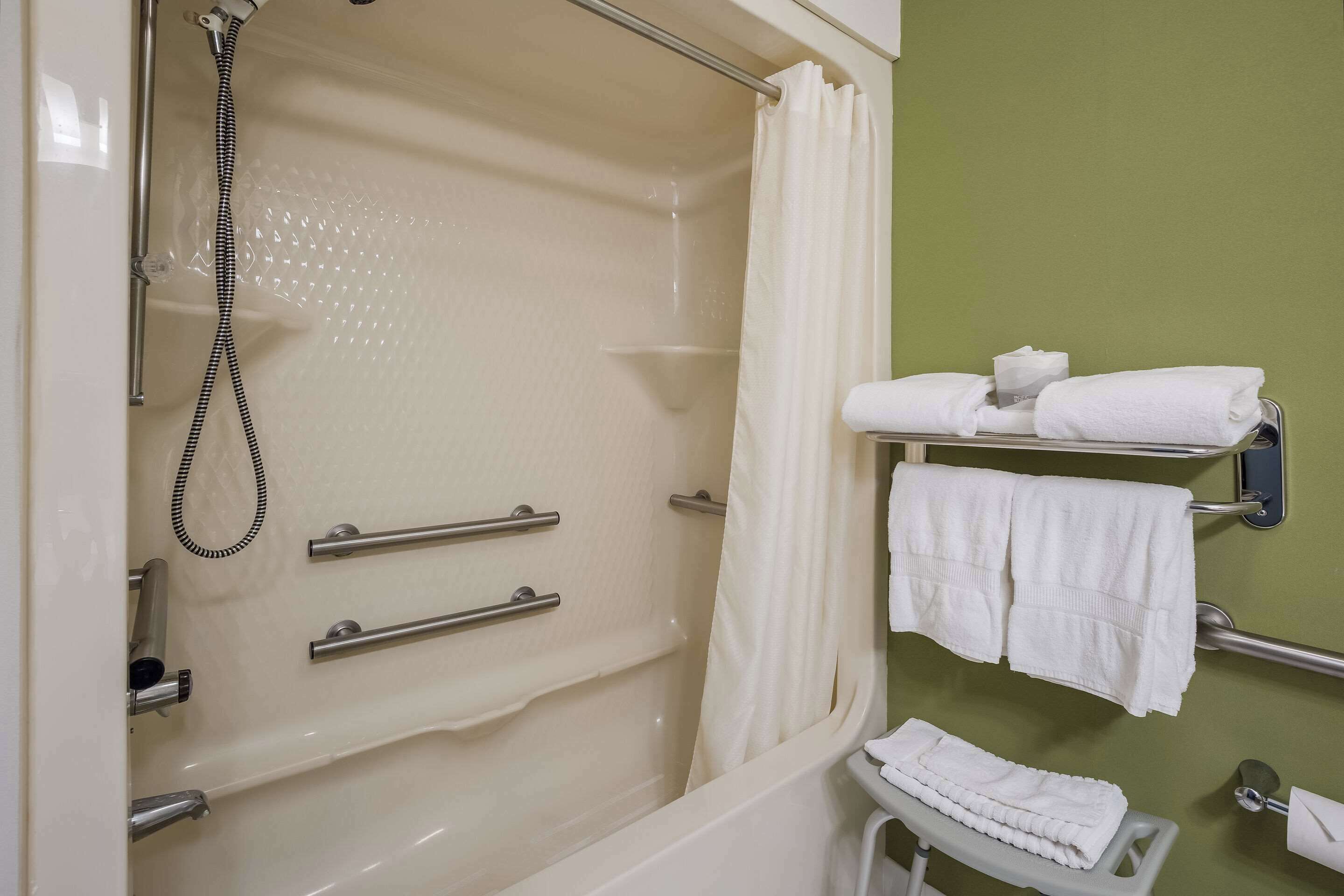 A bathroom with a bathtub, a shower, and a towel rack with towels.