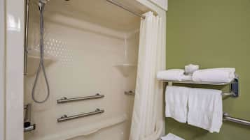 A bathroom with a bathtub, a shower, and a towel rack with towels.