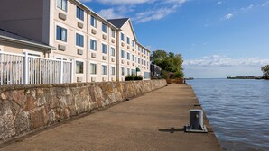 A waterfront hotel with a stone wall and a row of rooms.