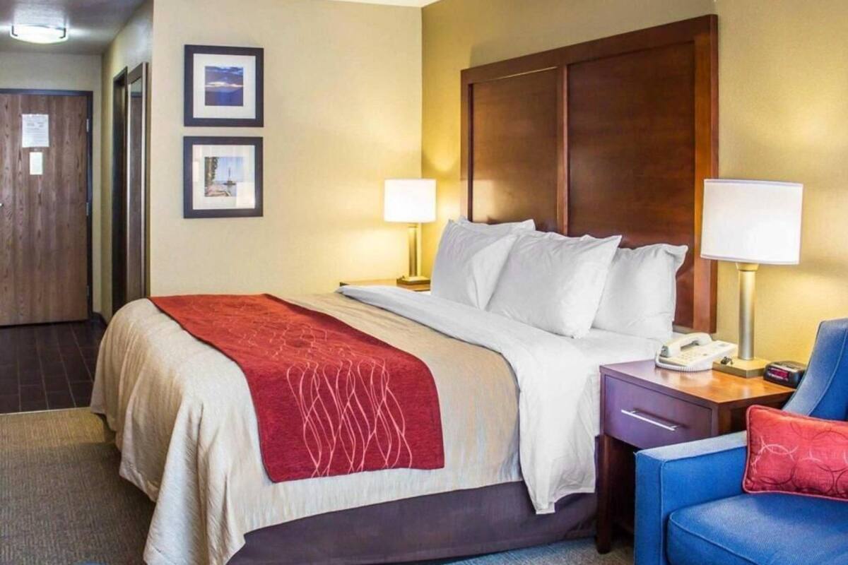 Habitación de hotel con cama, lámparas de noche, un escritorio con teléfono y una silla.