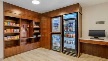 Una kitchenette con armarios de madera, un refrigerador y un microondas.