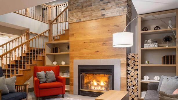 A modern living room with a fireplace, wooden staircase, and a cozy seating area.