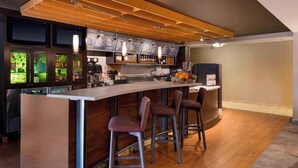 A modern bar area with a wooden ceiling, bar stools, and a menu board. - Courtyard by Marriott Akron Fairlawn (Akron)