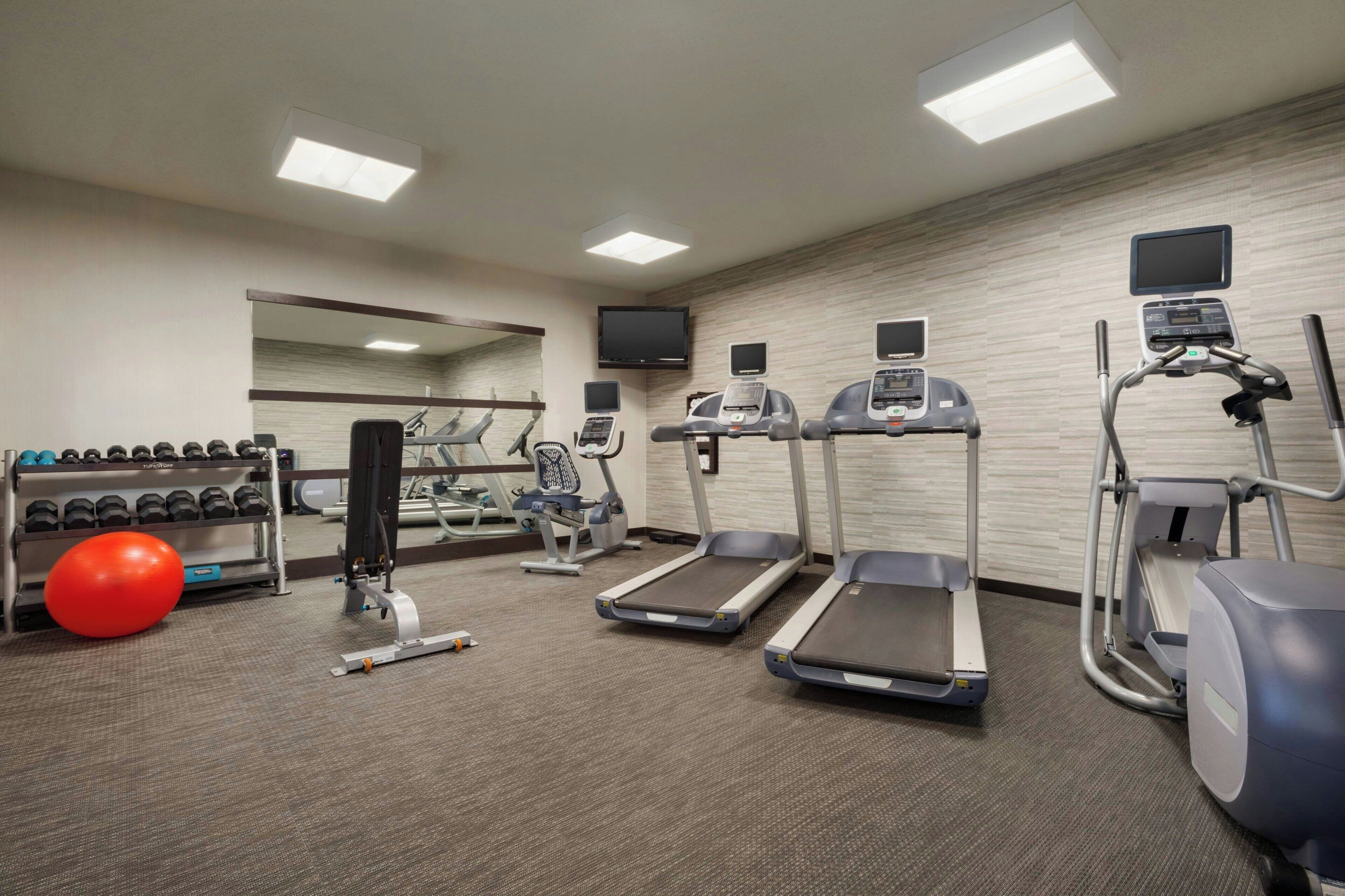 Un gimnasio con cintas de correr, elípticas y mancuernas.