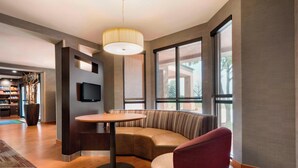 A modern hotel lobby with a round table, a red chair, a sofa, and large windows. - Courtyard by Marriott Akron Fairlawn (Akron)