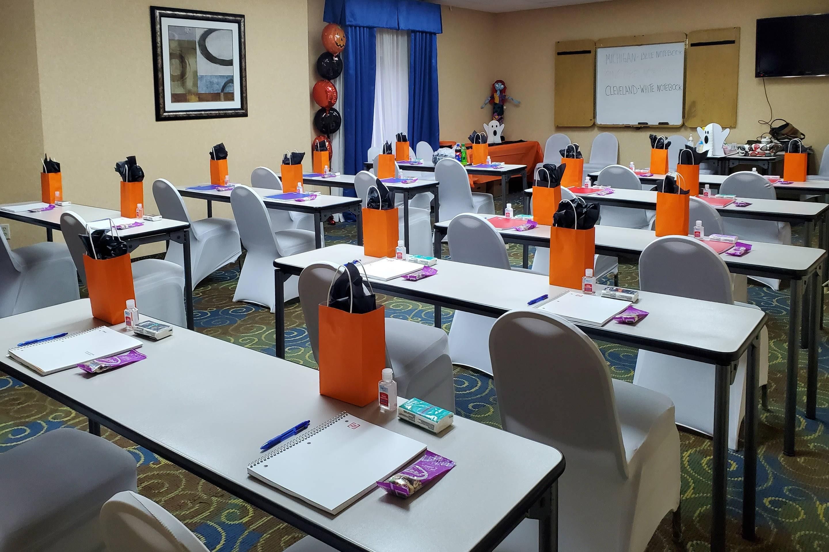 A conference room with tables, chairs, and orange gift bags.