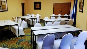 Uma sala de conferências com várias mesas e cadeiras, um tapete estampado e quadros decorativos nas paredes.