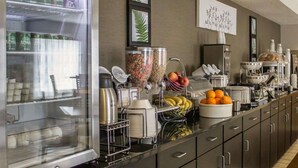 Un buffet proposant une variété d’aliments et de boissons, notamment des céréales, des fruits et un coin café.