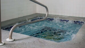 Un bain à remous doté d’une rampe de sécurité en métal et d’un revêtement en carrelage.