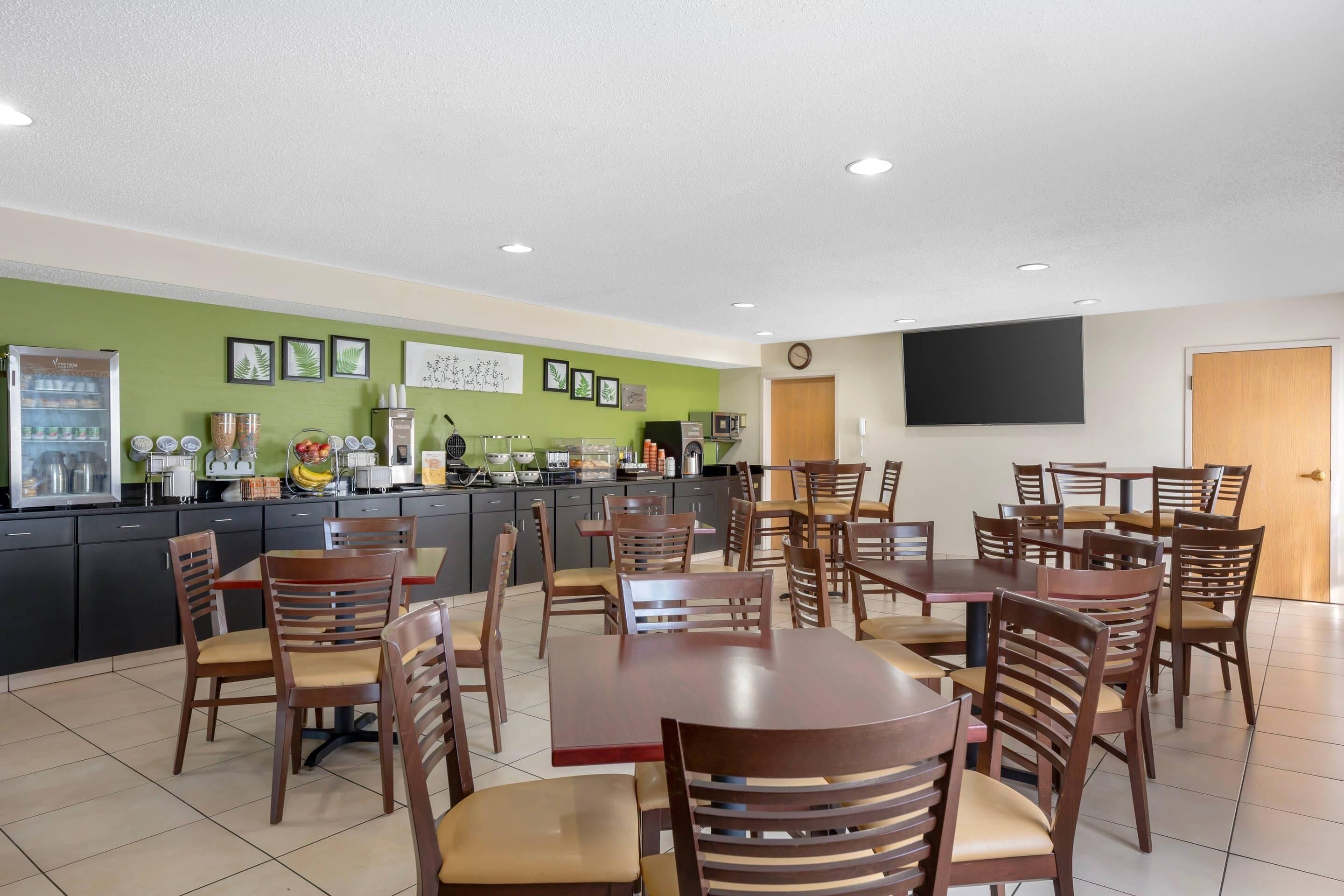 Un restaurante con varias mesas y sillas, una barra con dispensador de bebidas y cuadros en la pared.