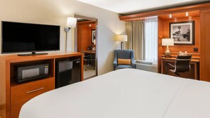 A hotel room with a bed, a TV, a desk with a chair, a microwave, and a lamp. - Comfort Inn Oxford - University Area (Oxford)