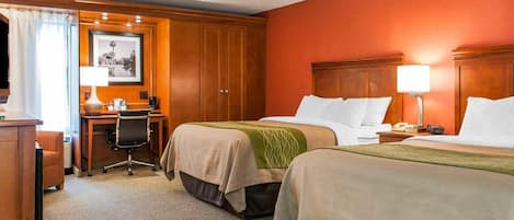 A hotel room with two beds, a desk, a chair, and a desk lamp.