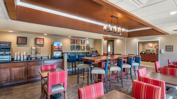 A restaurant with wooden tables and red upholstered booths, a bar area, and a kitchen visible in the background. - Comfort Inn Oxford - University Area (Oxford)