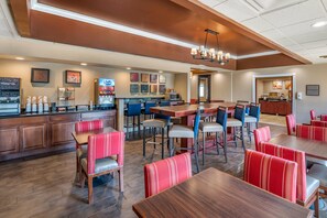 A restaurant with wooden tables and red upholstered booths, a bar area, and a kitchen visible in the background. - Comfort Inn Oxford - University Area (Oxford)