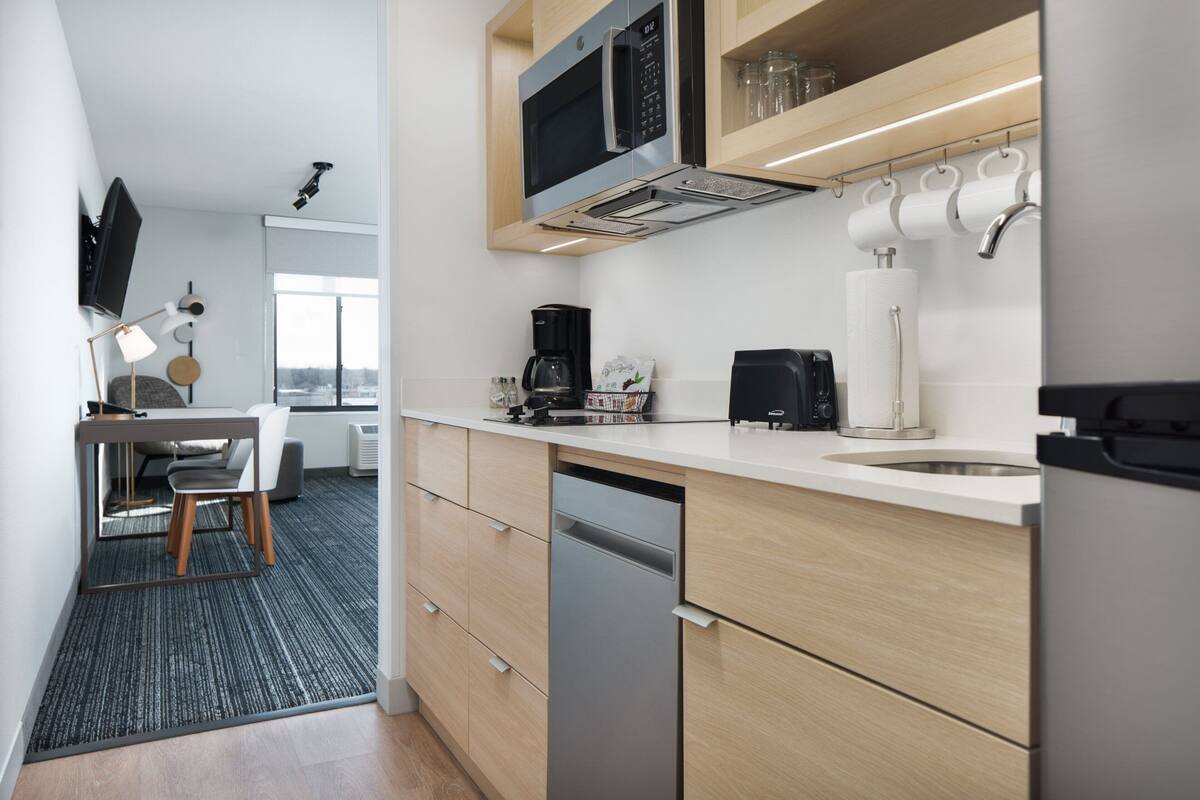 A modern kitchen with a dishwasher, microwave, coffee maker, and a dining area with a table and chairs.