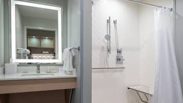 A modern bathroom with a large mirror, a sink, and a shower area.
