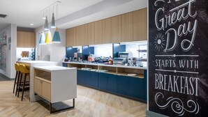 A modern kitchen with a breakfast bar, pendant lights, and a sign that reads "A Great Day Starts with Breakfast." - TownePlace Suites by Marriott Sidney (Sidney)