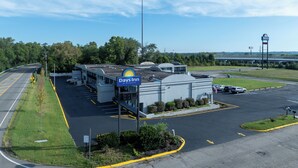 A Days Inn by Wyndham with a parking lot, a road curving to the left, and a bridge in the background. - Days Inn & Suites by Wyndham Dayton North (Dayton)