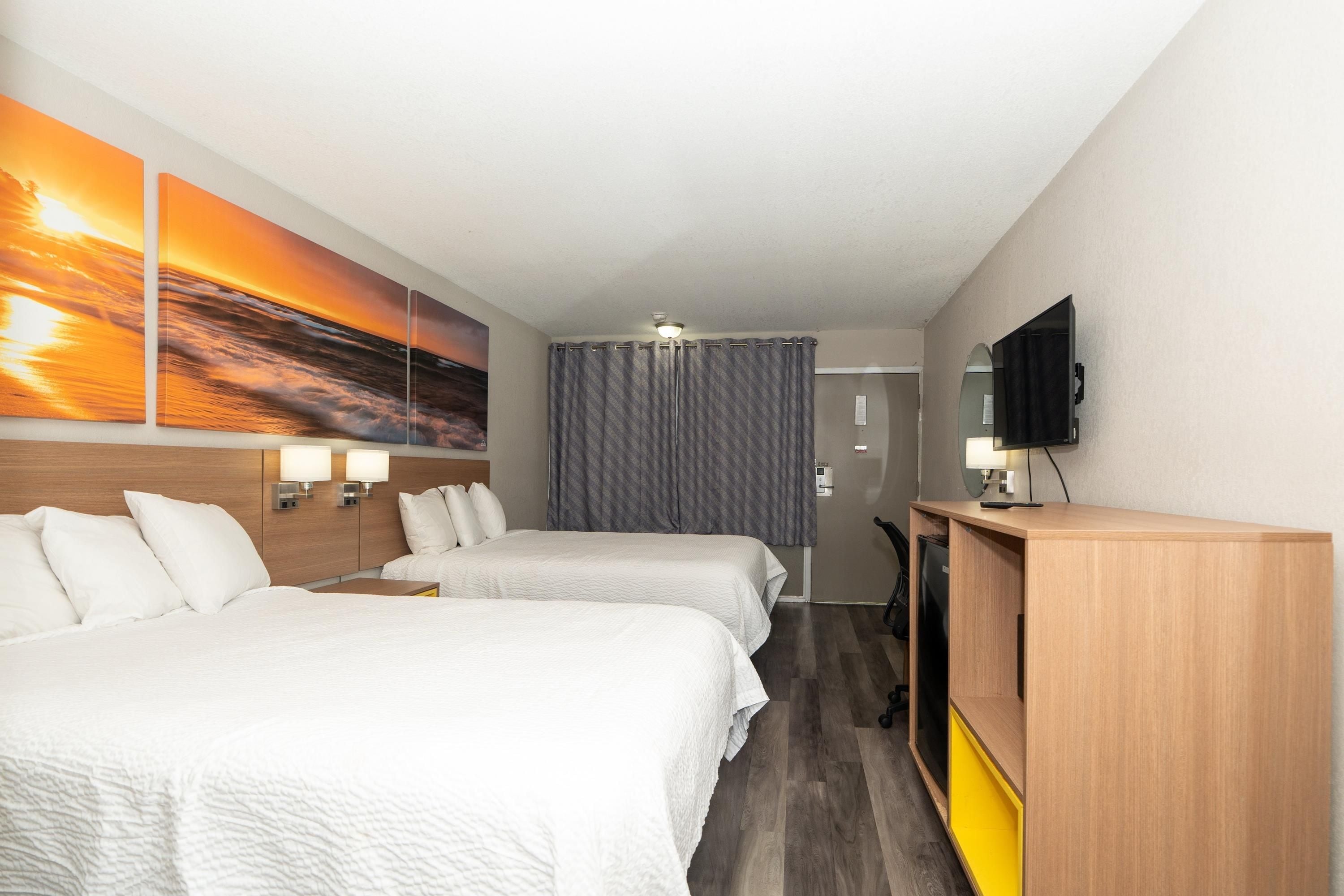 Une chambre d’hôtel avec deux lits, une télévision, un bureau et une porte de salle de bain.