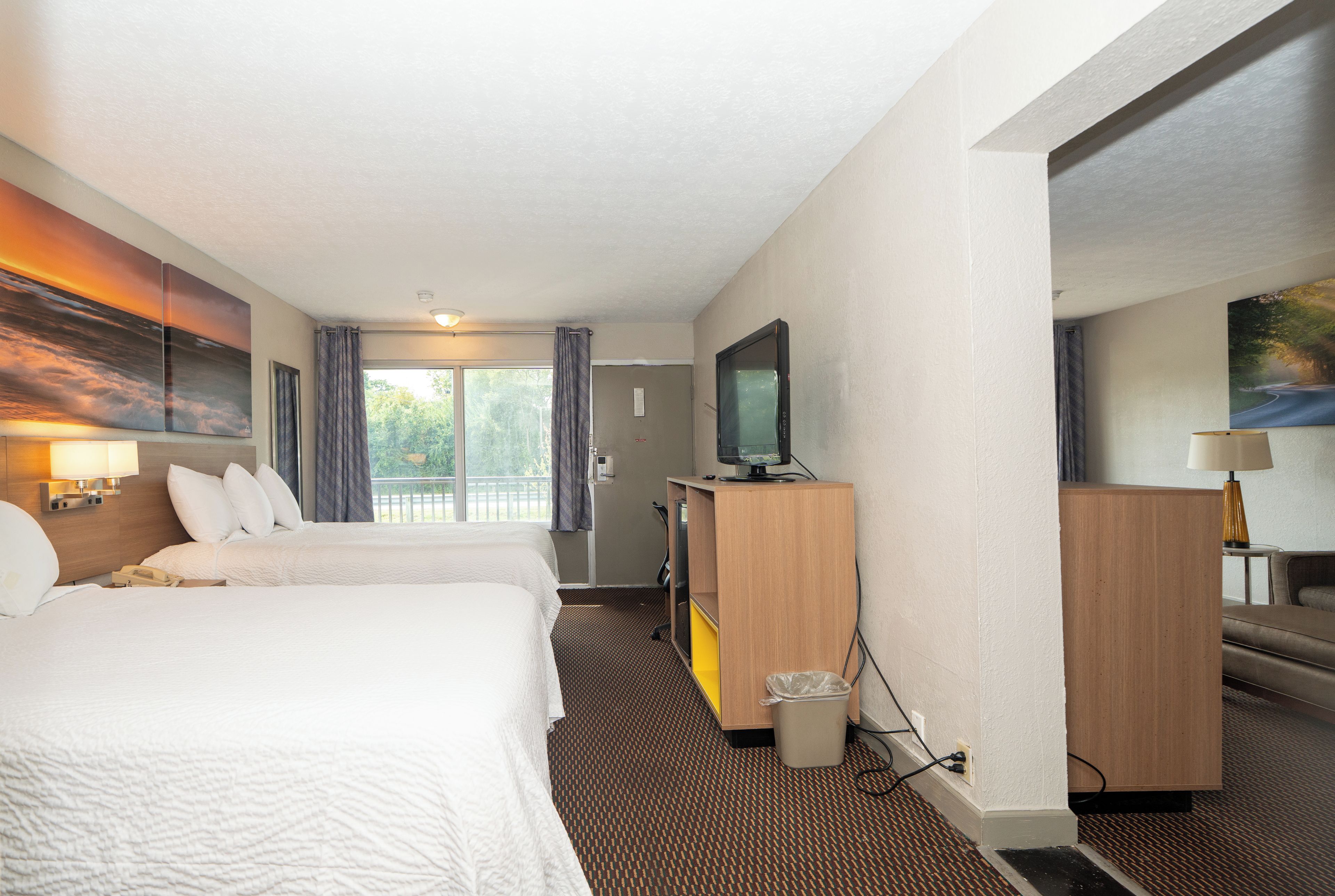 Habitación de hotel con dos camas, televisión, escritorio y un cuadro en la pared.
