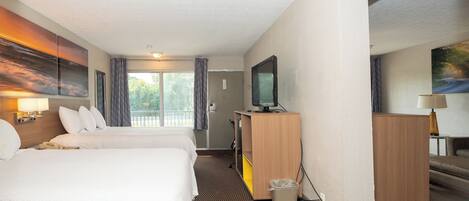 A hotel room with two beds, a television, a desk, and a painting on the wall.