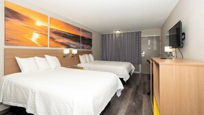 A hotel room with two beds, a television, and a view of the sunset. - Days Inn & Suites by Wyndham Dayton North (Dayton)