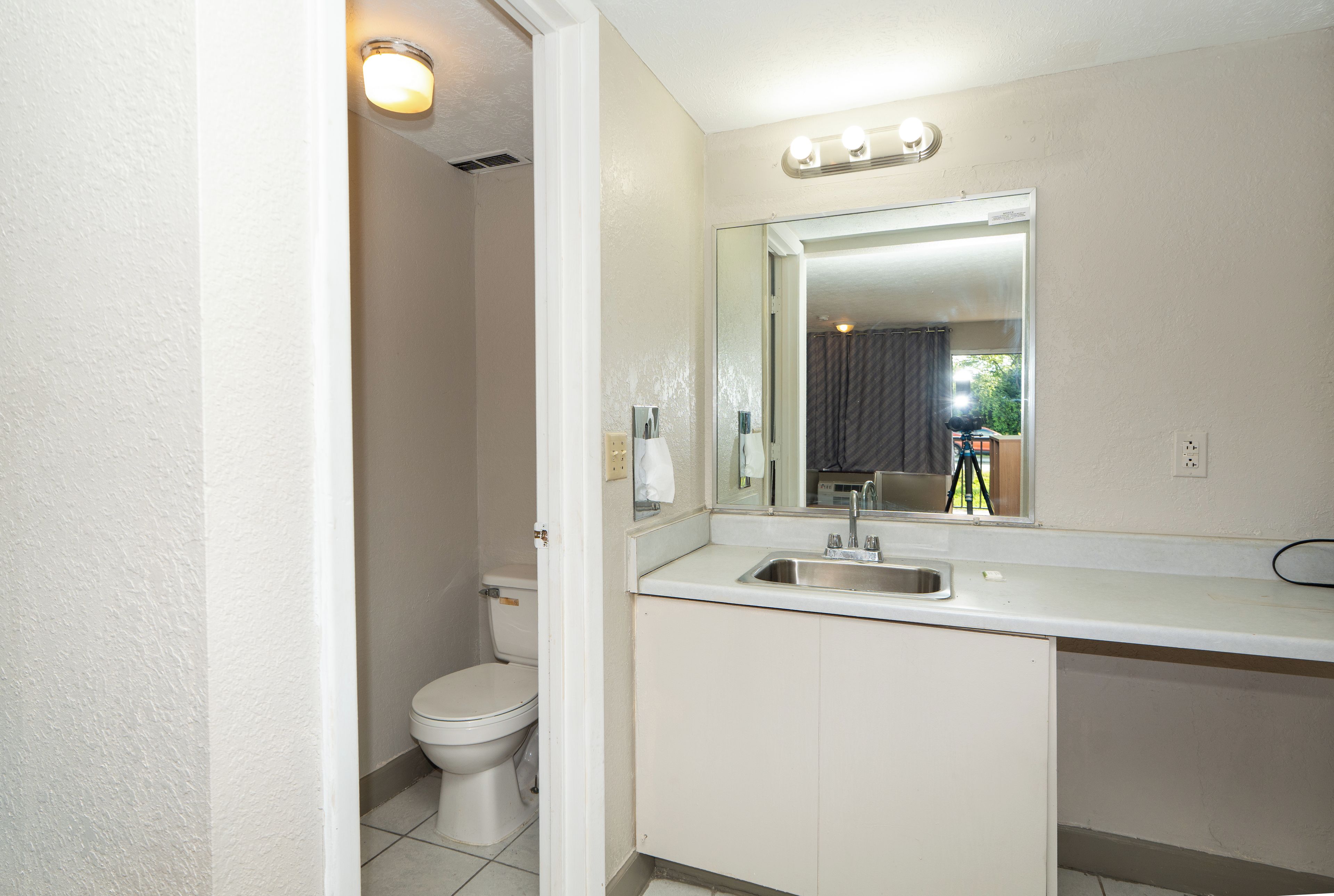 A bathroom with a toilet, a sink, and a mirror.