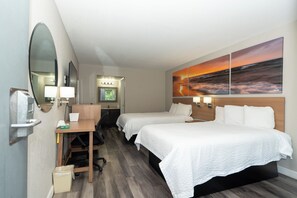A hotel room with two beds, a desk with a chair, a trash bin, a mirror, and a painting of a sunset over the ocean. - Days Inn & Suites by Wyndham Dayton North (Dayton)