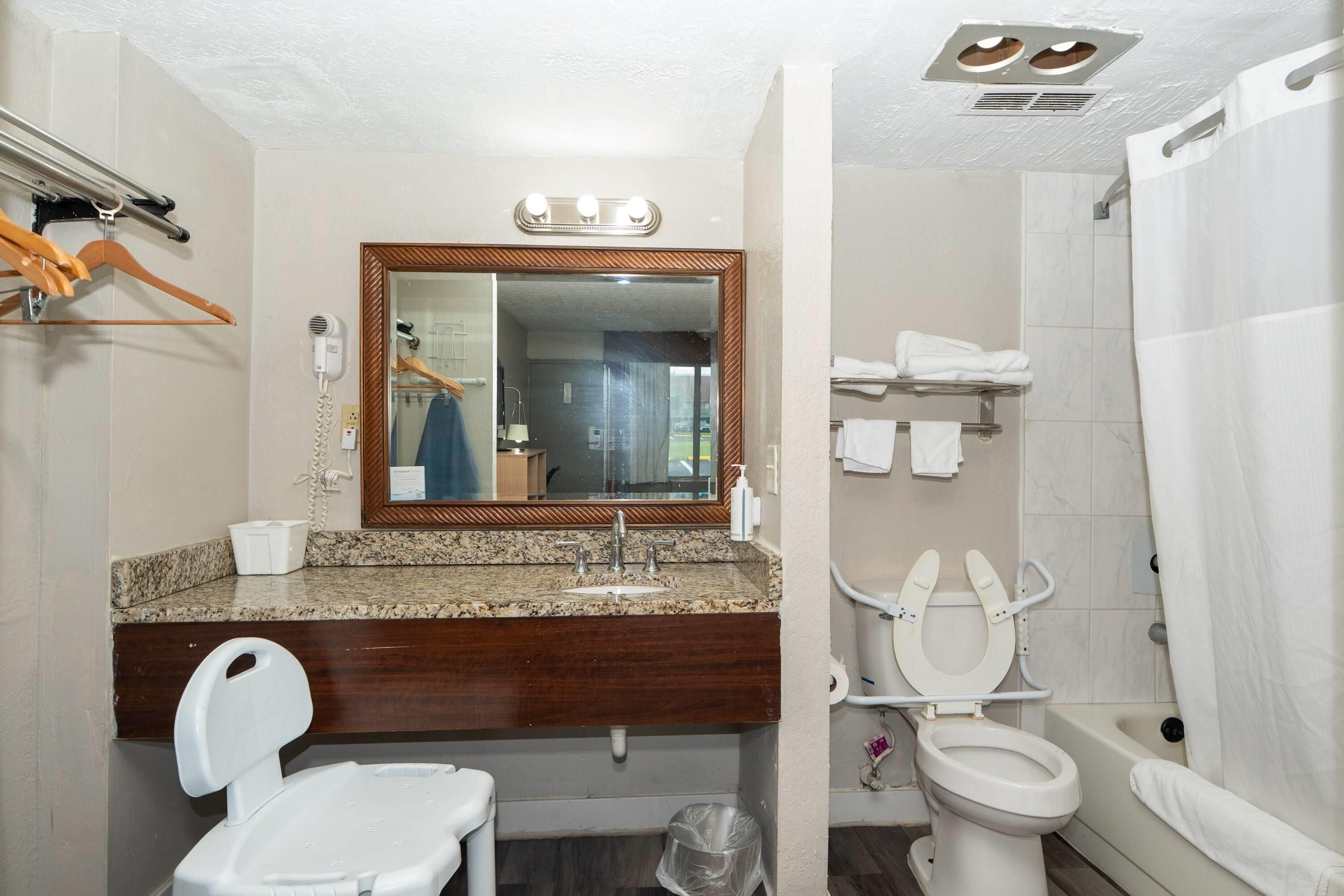 A bathroom with a vanity, a mirror, a toilet, and a shower.