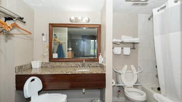 A bathroom with a vanity, a mirror, a toilet, and a shower.