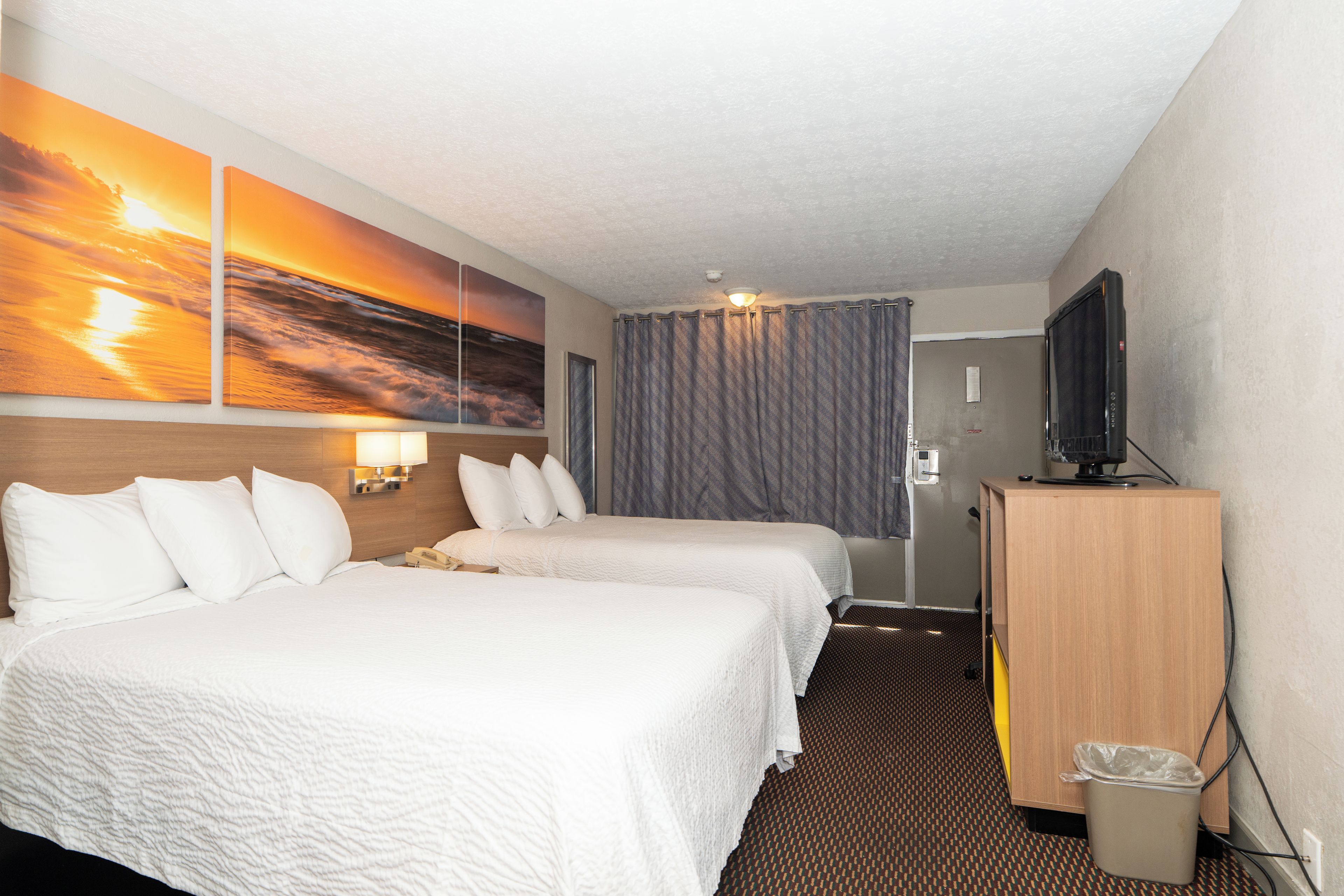 A hotel room with two beds, a television, a desk, and a bathroom door.