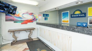A reception area with a reception desk, a 'No Pets' sign, a 'Manager On Duty' sign, and a 'Days Inn' sign. - Days Inn & Suites by Wyndham Dayton North (Dayton)