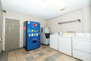A laundry room with a blue vending machine, a Whirlpool washer, and a dryer. - Days Inn & Suites by Wyndham Dayton North (Dayton)