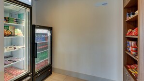 Ein Kühlregal mit verschiedenen Tiefkühlprodukten und Getränken, ein Gefrierbereich und eine Ablage mit verpackten Snacks.