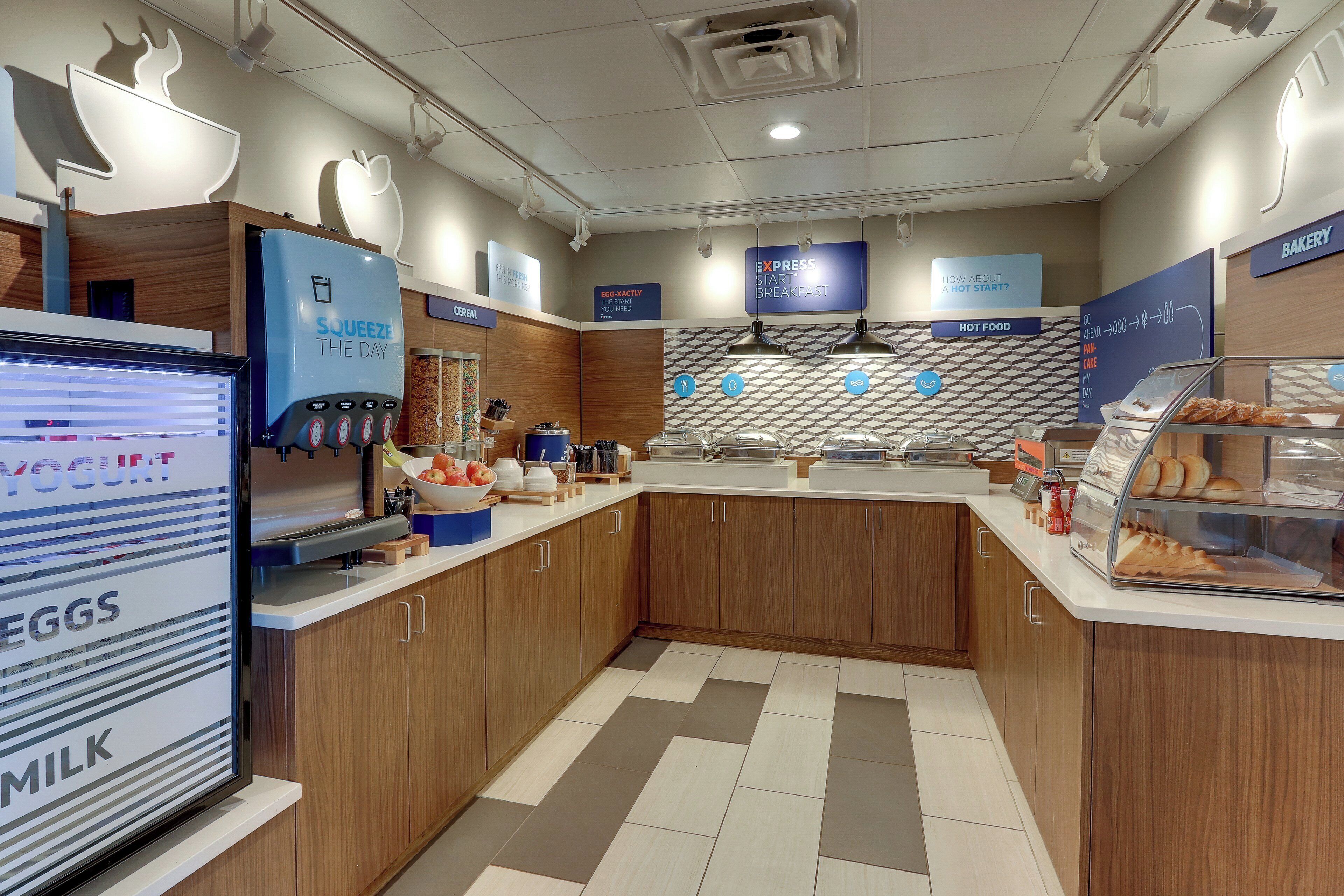 Un espace dédié au petit-déjeuner, équipé d’un écran numérique affichant le menu, d’un distributeur de yaourts et d’un présentoir de produits de boulangerie.