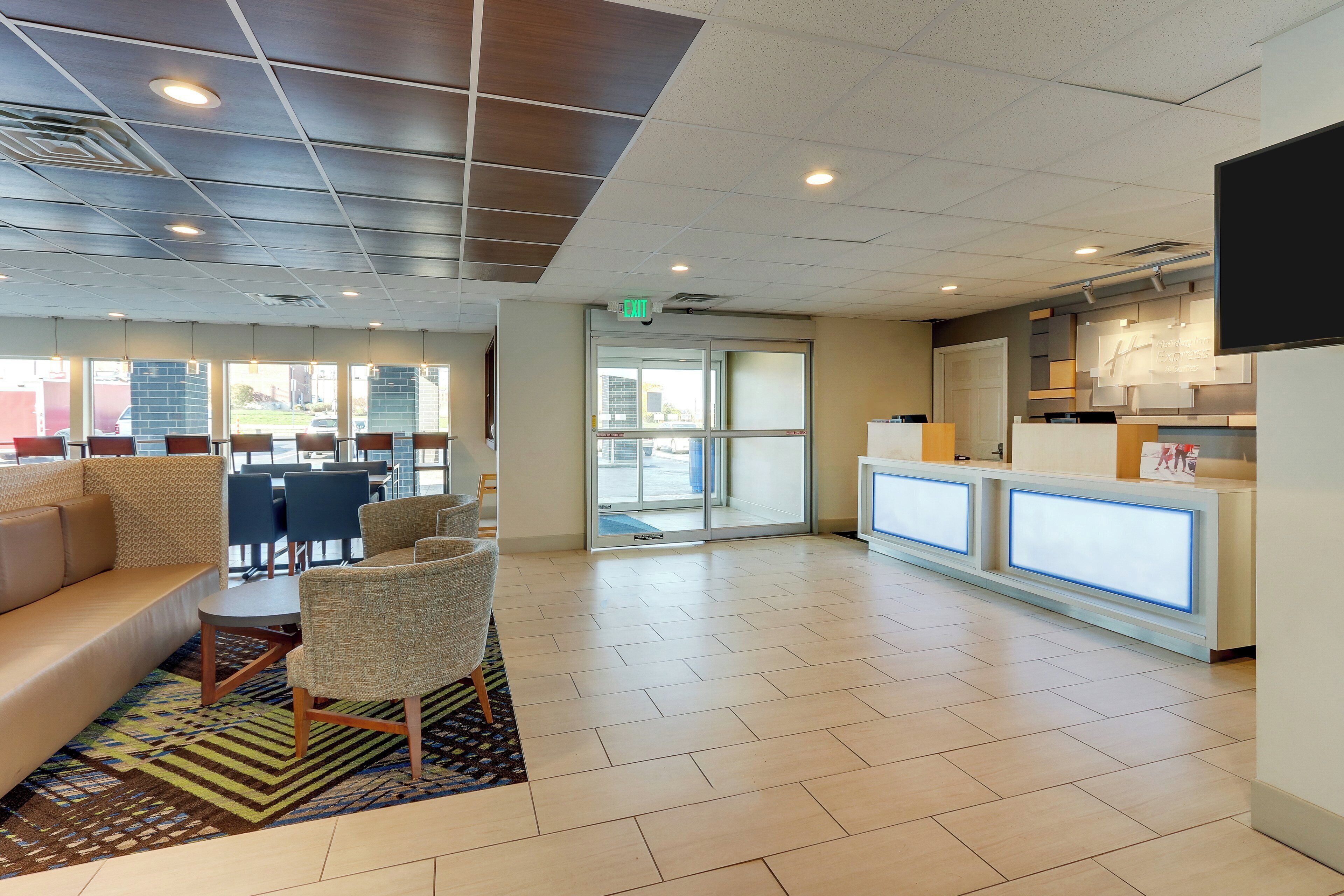 A hotel lobby with a reception desk, seating area, and a view of the outside.