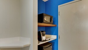 Eine Küchenzeile mit einer Mikrowelle, einer Kaffeemaschine und einem Kühlschrank.