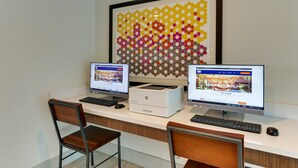 Ein moderner Schreibtisch mit zwei Computern, einem Drucker und zwei Stühlen.