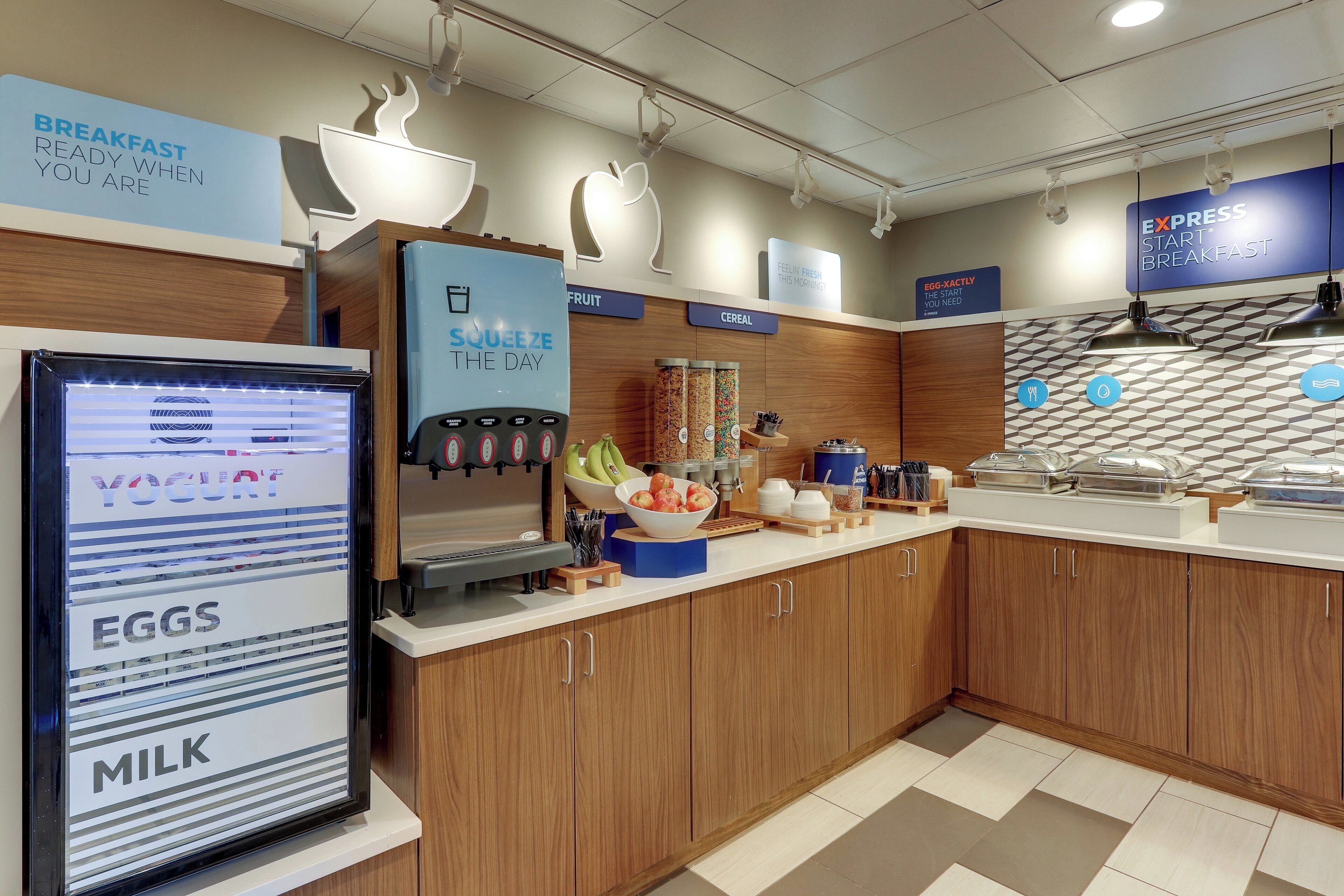 A breakfast area with a refrigerator, a coffee machine, and a bowl of fruit.