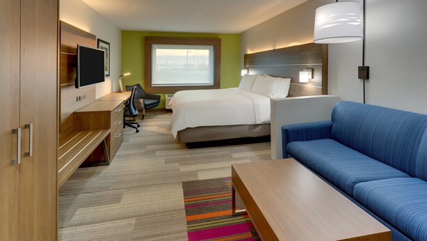 Ein modernes Hotelzimmer mit Bett, Sofa, Schreibtisch und Fernseher.