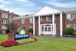 Un hotel Days Inn con fachada de ladrillo, una entrada amplia con puertas dobles y un letrero con el nombre del hotel.