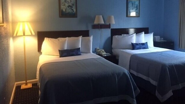 A hotel room with two beds, a nightstand, a lamp, and two wall-mounted lamps. - Days Inn by Wyndham Cleveland Lakewood (Lakewood)